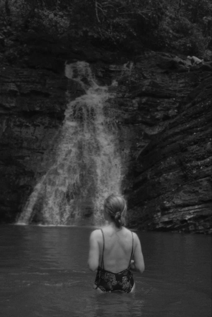 woman in the pool below a jungle waterfall in costa rica